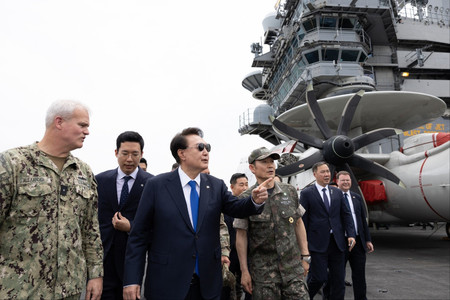 ２５日、韓国南部・釜山に寄港中の米海軍の原子力空母「セオドア・ルーズベルト」に乗艦した尹錫悦大統領（左から３人目）（韓国大統領府提供・時事）