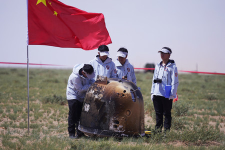 帰還した中国無人探査機「嫦娥６号」の回収作業を行う関係者ら＝２５日、内モンゴル自治区（ＡＦＰ時事）