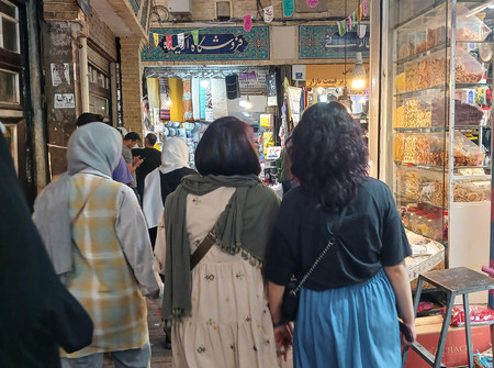 イランの首都テヘランで、頭部を覆うスカーフを着けずに買い物をする女性（右の２人）＝６月２６日