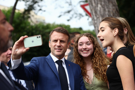 ６月３０日、北部ブローニュシュルメール近郊で、フランス国民議会選の第１回投票を終え、支援者と写真を撮るマクロン大統領（右から３人目）（ＥＰＡ時事）