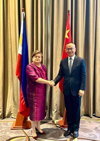 ２日、マニラで握手する中国の陳暁東外務次官（右）とフィリピンのラザロ外務次官（比外務省提供・時事）