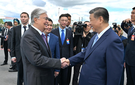 ２日、カザフスタンの首都アスタナの空港で、トカエフ大統領（左）の出迎えを受ける中国の習近平国家主席（カザフ大統領府提供）（ＡＦＰ時事）