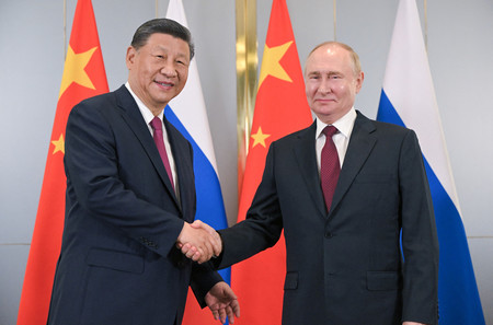 ３日、カザフスタンの首都アスタナで、中国の習近平国家主席（左）と握手するロシアのプーチン大統領（ＡＦＰ時事）