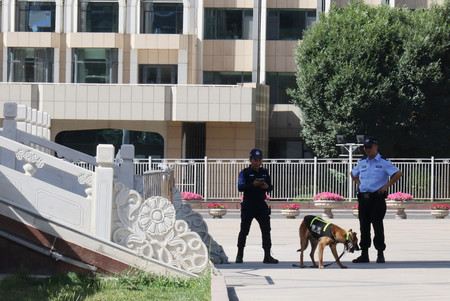 中国・新疆ウイグル自治区のウルムチ市中心部にある人民広場で警察犬を連れて警戒に当たる警官＝６月２８日