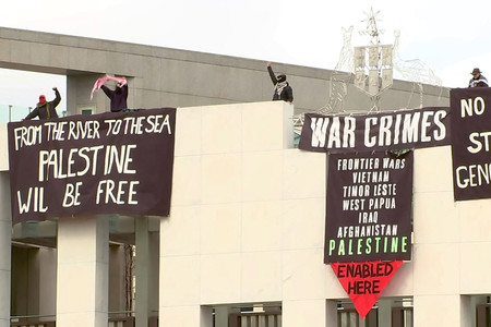 ４日、オーストラリアの首都キャンベラで、国会議事堂の屋根からパレスチナ自治区ガザでの紛争に抗議する幕を掲げる活動家（豪公共放送ＡＢＣの映像より）（ＡＦＰ時事）