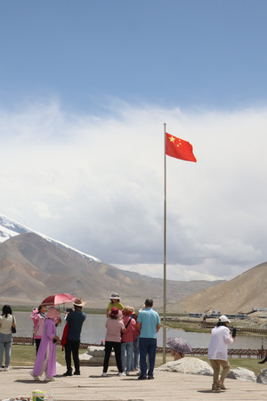 中国新疆ウイグル自治区カシュガルの観光地に掲げられた中国国旗と、訪れた漢族の観光客ら＝６月２７日