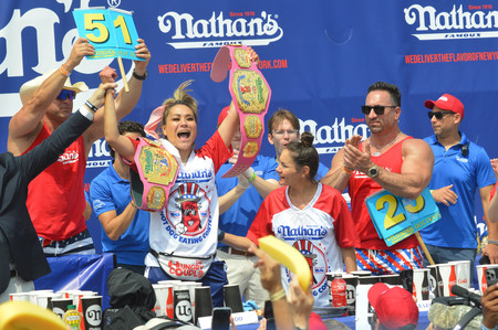 ４日、ニューヨークで開かれたホットドッグ早食い大会で１０度目の優勝を果たした須藤美貴さん（中央左）