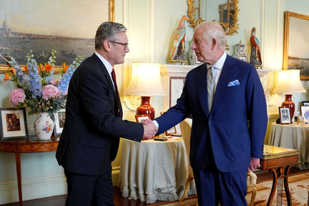 ５日、ロンドンのバッキンガム宮殿で、握手を交わすスターマー英新首相（左）とチャールズ国王（ＡＦＰ時事）