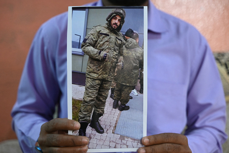 ロシア軍の戦闘服を着たインド人男性の写真を示す男性の兄弟＝２月２２日、インド・ハイデラバード（ＡＦＰ時事）