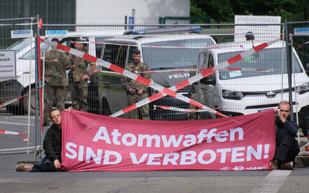 ドイツ西部ネルフェニヒの空軍基地前で抗議する国際ＮＧＯ「核兵器廃絶国際キャンペーン（ＩＣＡＮ）」独支部のメンバーら（手前）＝６日