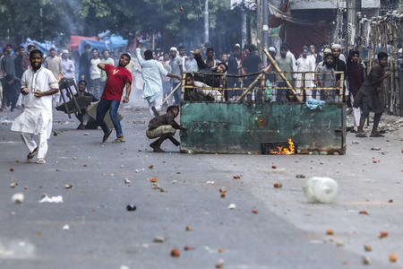１９日、バングラデシュの首都ダッカで、警官隊と衝突し、投石するデモ隊（ＡＦＰ時事）