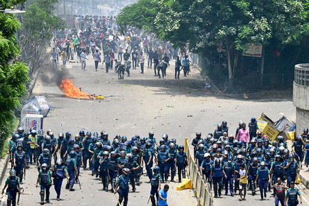 バングラデシュの首都ダッカで、衝突するデモ隊（奥）と警官隊＝１８日（ＡＦＰ時事）