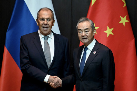 ２５日、ビエンチャンで、ロシアのラブロフ外相（左）と握手する中国の王毅共産党政治局員兼外相（ＡＦＰ時事）