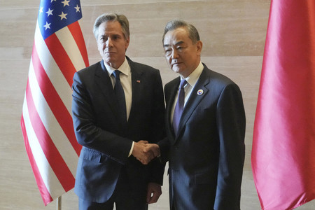 ２７日、ビエンチャンで握手するブリンケン米国務長官（左）と中国の王毅共産党政治局員兼外相（ＡＦＰ時事）