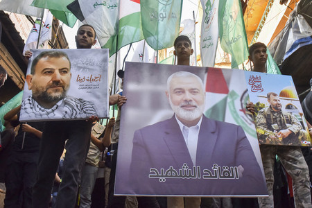 暗殺されたイスラム組織ハマス最高指導者ハニヤ氏の写真（中央）を掲げ、抗議する人々＝７月３１日、ベイルート南郊（ＡＦＰ時事）