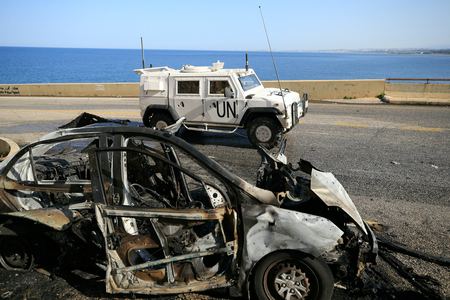 イスラエル軍の攻撃で大破した車の脇を通る国連レバノン暫定軍（ＵＮＩＦＩＬ）の車両＝３月２日、レバノン南部（ＡＦＰ時事）