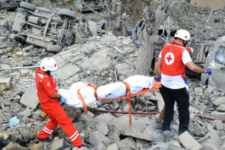 １４日、レバノン北部の村で、イスラエル軍による空爆の現場から遺体を搬出する医療関係者（ＡＦＰ時事）