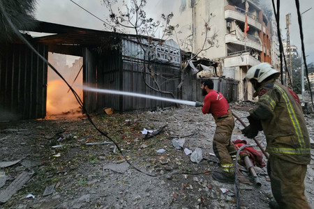 ２４日、レバノンの首都ベイルート南郊で、イスラエル軍空爆現場の消火活動に当たる消防隊員ら（ＡＦＰ時事）