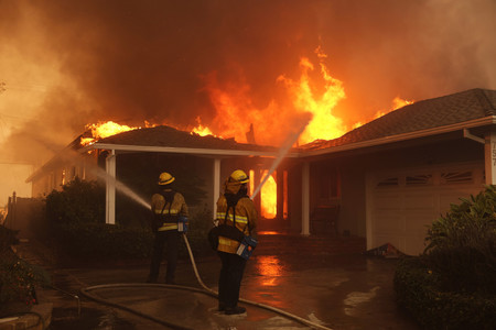 ８日、米西部カリフォルニア州ロサンゼルスのパシフィックパリセーズ地区で山火事の消火に当たる消防士（ＥＰＡ時事）