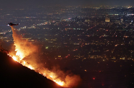 ８日、米カリフォルニア州ロサンゼルス近郊で起きた山火事で、放水する消防隊のヘリコプター（ＡＦＰ時事）