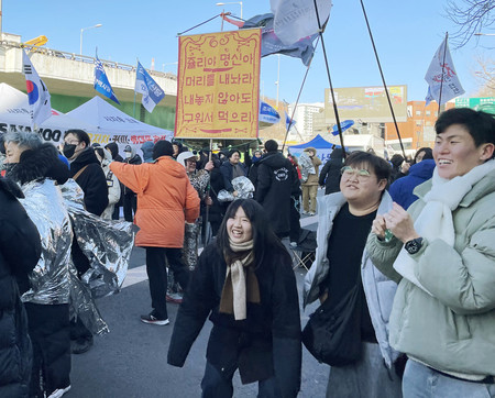 １５日、ソウルの韓国大統領公邸付近で、尹錫悦大統領拘束の報を受け喜ぶ市民ら