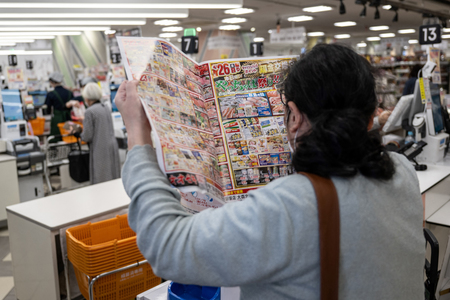 東京都内のスーパーで、チラシをチェックする買い物客＝２０２４年４月（ＡＦＰ時事）