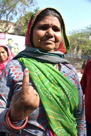 インドのデリー首都圏議会選で、投票を終えたことを示す指のインクを見せる女性＝５日、ニューデリー