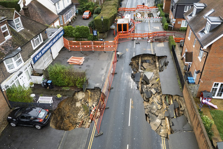 ２０日、英南部サリー州ゴッドストーンの住宅街で陥没した道路（ＥＰＡ時事）