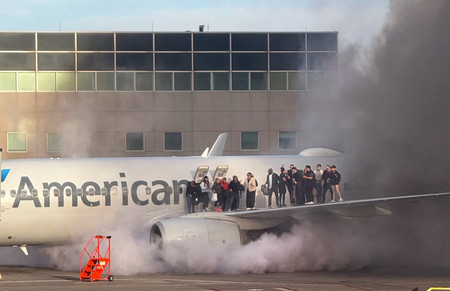 １３日、米西部コロラド州のデンバー国際空港で、煙を上げる旅客機から避難する乗客（ＡＦＰ時事）