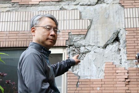 地震で壊れたマンションの外壁を示す李国隆さん＝１日、台湾東部花蓮県