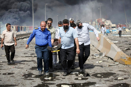 ２６日、大規模な爆発が起きたイラン南部バンダルアバスの港湾地区で、負傷者を搬送する人々（ＡＦＰ時事）
