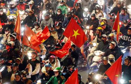 ハノイの路上で国旗を掲げるベトナムのサッカーファンたち=2025年1月6日(EPA時事)
