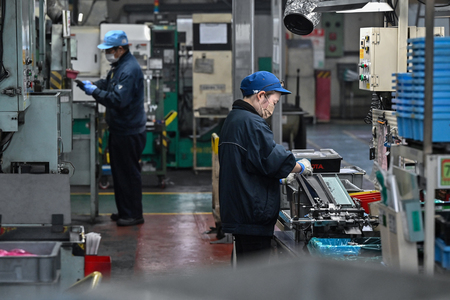 愛知県碧南市の自動車部品工場で、部品を検査する従業員=1日(AFP時事)