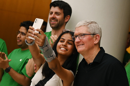 インドのニューデリーにできた店舗で、来店客と写真を撮る米アップルのクック最高経営責任者(CEO)(右)=2023年4月(AFP時事)