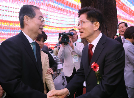 5日、ソウルで握手を交わす韓国与党「国民の力」大統領選候補の金文洙前雇用労働相(右)と無所属の韓悳洙前首相(EPA時事)