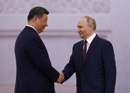 8日、モスクワのクレムリン(ロシア大統領府)で握手するプーチン大統領(右)と中国の習近平国家主席(ロイター時事)