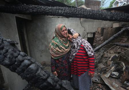 8日、インドとパキスタンの係争地カシミール地方の村サラマバードで、パキスタン軍の攻撃によって損壊した家屋の中で悲しむ女性ら(EPA時事)