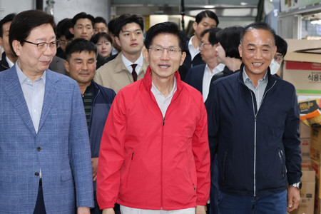 12日、ソウル市内の生鮮食品市場で選挙活動を行う保守系与党「国民の力」の金文洙前雇用労働相(中央)(AFP時事)