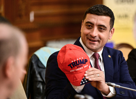 トランプ米大統領への支持を示す帽子を掲げるルーマニアの極右政党「ルーマニア人統一同盟」のシミオン党首=2024年11月、ブカレスト(AFP時事)