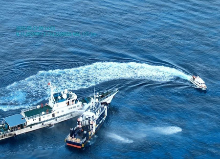 フィリピンの漁業水産資源局の船(中央)に放水銃を発射する中国海警局の船舶(左)=21日、南シナ海・南沙(英語名スプラトリー)諸島(フィリピン沿岸警備隊提供・時事)