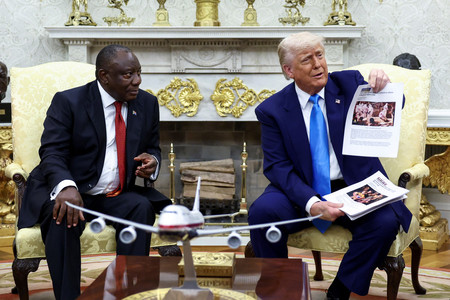 南アフリカのラマポーザ大統領(左)との会談で、写真付きの記事を掲げるトランプ米大統領=21日、ワシントン(ロイター時事)