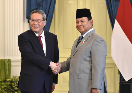 25日、ジャカルタで中国の李強首相(左)と握手するインドネシアのプラボウォ大統領