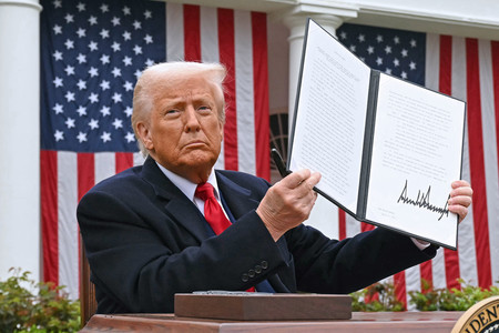 ホワイトハウスで相互関税に関する大統領令を掲げるトランプ氏=4月2日、ワシントン(AFP時事)