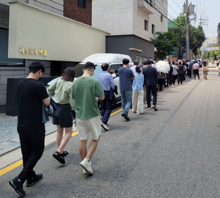韓国大統領選の期日前投票のため投票所の列に並ぶ有権者=29日、ソウル