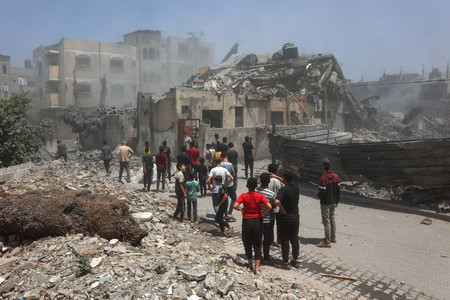 5月31日、パレスチナ自治区ガザ北部ガザ市で、イスラエル軍の攻撃を受けた建物を調べる人々(AFP時事)