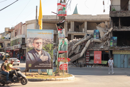 イスラエル軍が昨年10月の空爆で殺害したレバノン南部ナバティエの市長の写真看板(左)と地方選挙ポスター=5月24日