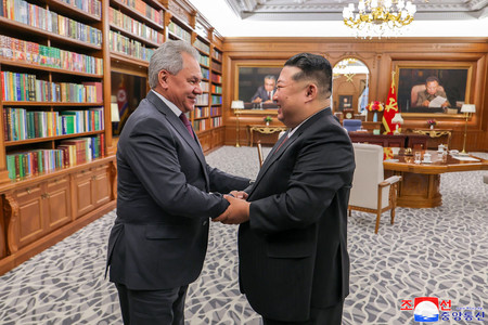 4日、平壌で握手する北朝鮮の金正恩朝鮮労働党総書記(右)とロシアのショイグ安全保障会議書記=朝鮮通信が5日配信(AFP時事)