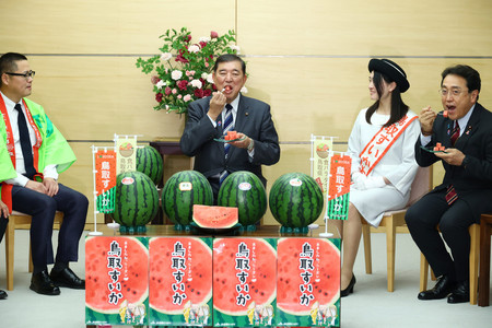 JA全農とっとりから「鳥取すいか」の贈呈を受け、試食する石破茂首相(中央)。右端は赤沢亮正経済再生担当相=10日午前、首相官邸