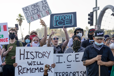 不法移民の取り締まりにデモ隊が抗議する中、プラカードを掲げる人たち＝８日、米ロサンゼルス（ＡＦＰ時事）