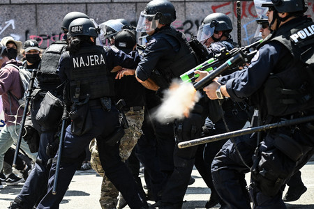 10日、米西部カリフォルニア州ロサンゼルスで、抗議活動参加者を拘束する警察(AFP時事)